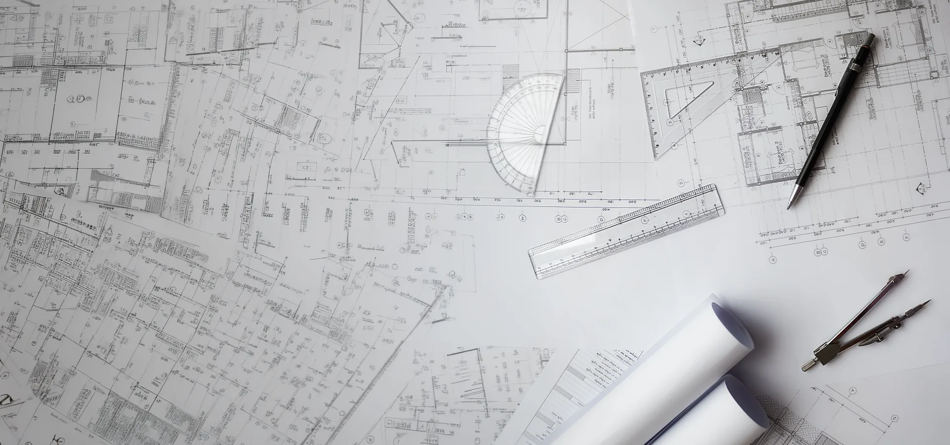 Architectural floor plans, ruler and drafting tools laid out on a desk