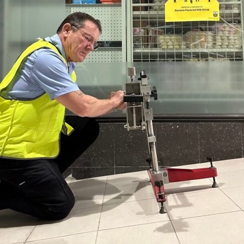 Bruce Whiteley operating a pendulum slip resistance tester on a tiled retail floor