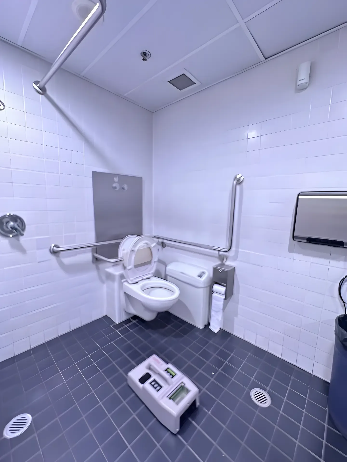 Slip testing equipment set up on the tiled floor of an accessible bathroom with grab rails