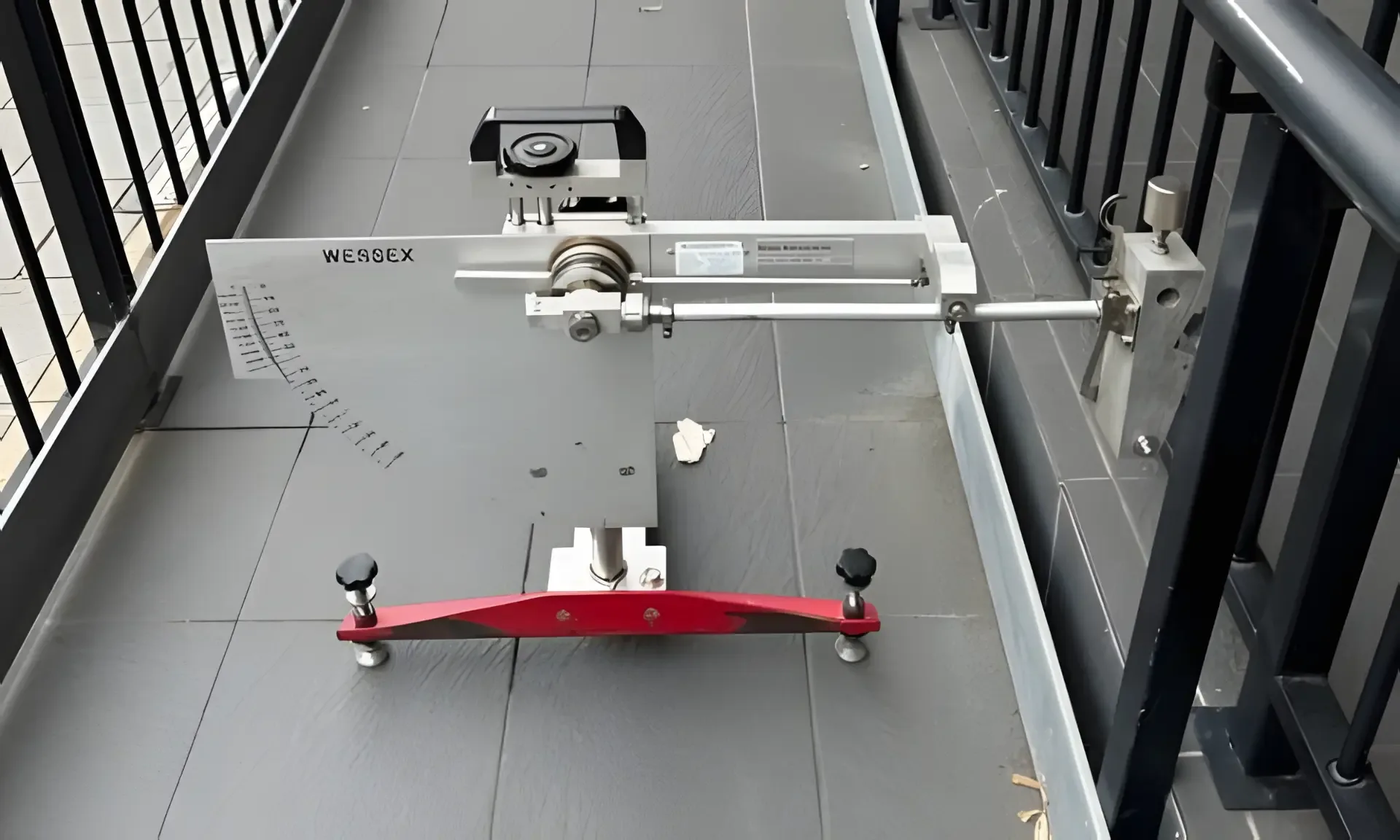 Wessex pendulum slip resistance tester set up on grey tiles of an external balcony walkway