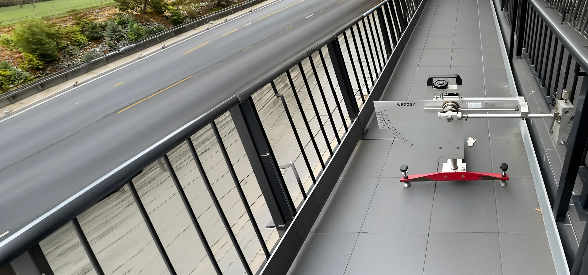 Wessex pendulum slip tester set up on a tiled pedestrian bridge walkway above a motorway